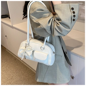 Detail view of white PU leather shoulder bag with pearl bow charm and dual straps on model