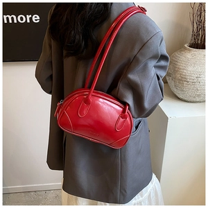Detail of red glossy PU leather shoulder bag with embossed logo worn on the shoulder