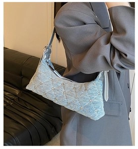 Detail view of light blue denim hobo bag featuring quilted patterns and silver rivets