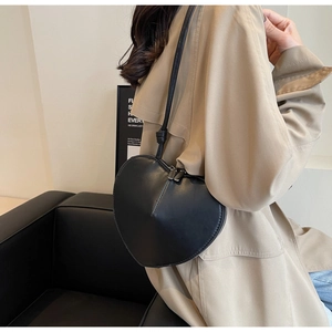 Dettaglio di una borsa a tracolla chic a forma di cuore in pelle nera indossata da una modella