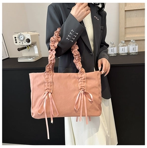 Vue détaillée du sac cabas en toile rose avec poignées plissées et nœuds décoratifs