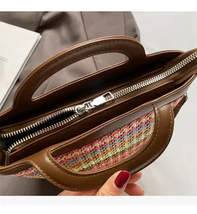 Detail of a smooth silver zipper closure on a colorful woven straw handbag