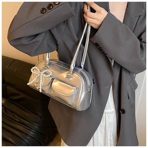 Detail of silver metallic PU bag featuring pearl bow and heart charm on a side view