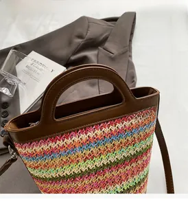 Detail of multi-colored woven straw handbag with brown leather straps and zip closure