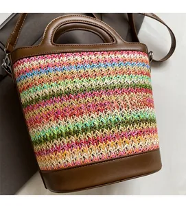 Close-up of woven straw bucket bag showing colorful wave patterns and brown leather trims
