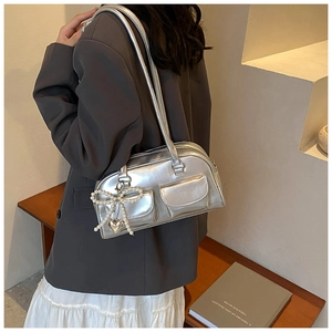 Detail of silver metallic PU shoulder bag featuring pearl bow and heart charms on a model