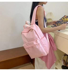Dettaglio dello zaino in nylon rosa chiaro con spallacci imbottiti e tasche laterali