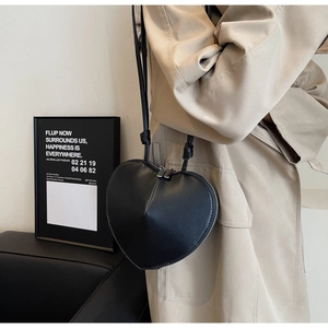Borsa a tracolla nera a forma di cuore abbinata a un trench coat beige