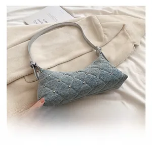 Detail of light blue denim crossbody bag with quilted diamond patterns and small rhinestones