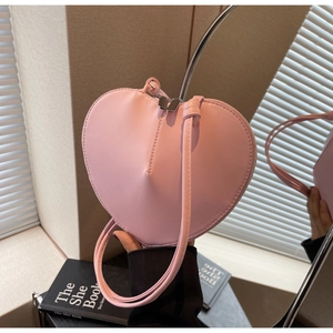 Dettaglio di una borsa a forma di cuore rosa con cerniera in argento e manico in pelle