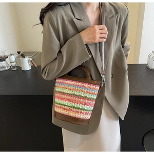 Detail of colorful woven straw crossbody bag with brown faux leather trim and strap