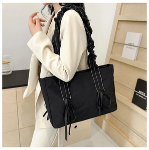 Détail de la bandoulière à volants avec surpiqûres blanches sur un sac fourre-tout noir