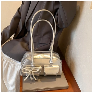 Detail of silver metallic PU handbag featuring front flap pockets and pearl bow charm
