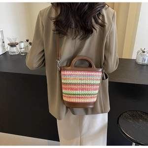 Detail showing colorful woven straw bucket bag with dark brown leather handle and strap