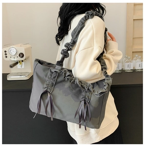 Vue détaillée du sac d'épaule gris avec bretelles à volants et nœuds décoratifs en ruban