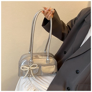 Detail of silver PU leather bag with metallic finish and pearl bow charm with heart pendant