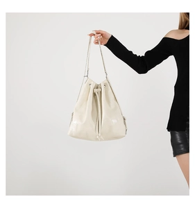 Detail of cream white bucket bag featuring geometric patchwork faux leather and drawstring