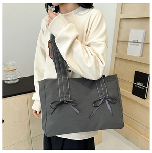 Détail du sac cabas en toile grise avec nœuds en ruban et longue bandoulière
