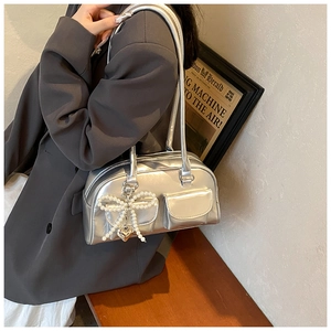 Detail of silver PU shoulder bag with pearl bow and heart charm on a gray blazer