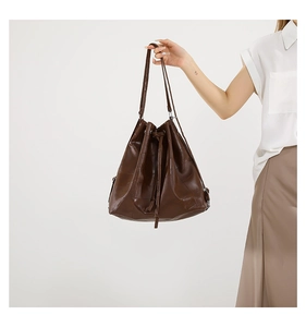 Detail of dark brown PU leather bucket bag with drawstrings and grid stitching texture