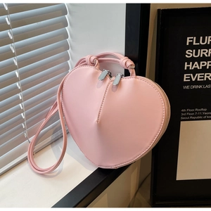 Vista dettagliata della borsa rosa a forma di cuore con cerniere argento e tracolla coordinata