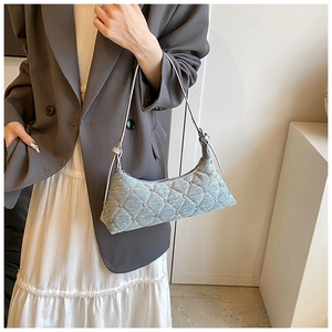Close-up of a light blue denim shoulder bag with quilted pattern and silver metal studs