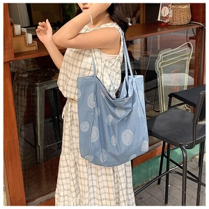 Detail of light blue denim tote bag with white smiley patterns for casual daily use