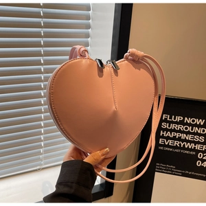 Dettaglio della borsa a tracolla rosa a forma di cuore con pelle opaca e doppia cerniera