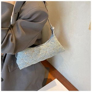 Detail of light blue denim shoulder bag with diamond quilting and silver rhinestones