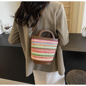 Close-up of a colorful woven bucket bag with brown leather trim and metal hardware hooks