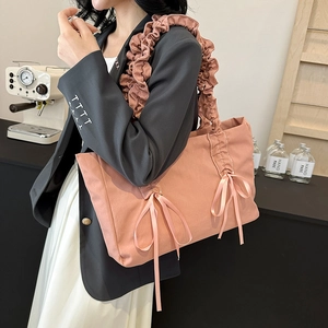Sac fourre-tout en toile rose avec nœud et bandoulière plissée porté par une femme