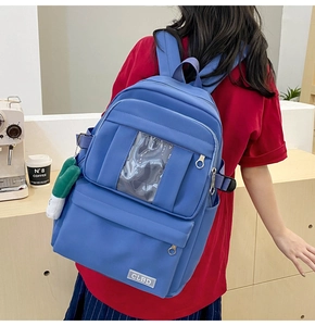Détail du sac à dos en nylon bleu vif avec poche transparente et porte-clé peluche vert