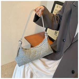 Detail view of denim crossbody bag with diamond quilting and silver rivet accents