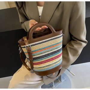Detail of multi-color striped straw bucket bag with brown leather handle and silver hardware