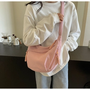 Detail of pink corduroy crescent crossbody bag showing striped texture and woven zipper