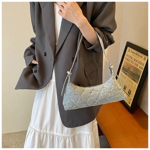 Close-up of blue denim baguette bag featuring quilted diamond pattern and stud details