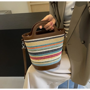 Detailed texture of colorful striped straw bucket bag with brown leather handles and strap