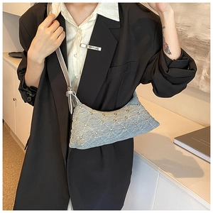 Detail of light blue denim crescent bag with quilted pattern and silver studs