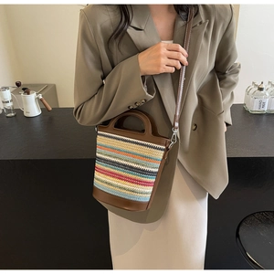 Detailed shot of a colorful striped straw bucket bag with dark brown leather handles
