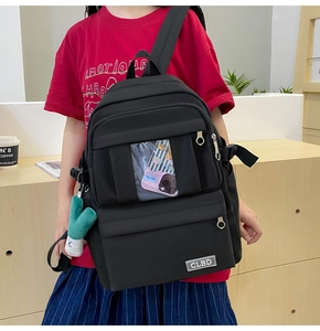 Détail d'un sac à dos en nylon noir avec une poche transparente et une peluche de légume