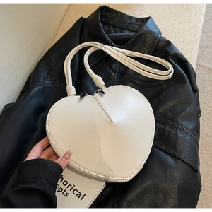 Dettaglio di una borsa a tracolla bianca a forma di cuore in pelle PU su giacca nera