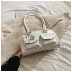 Trendy white glossy PU leather shoulder bag with pearl bow and heart charm on soft fabric