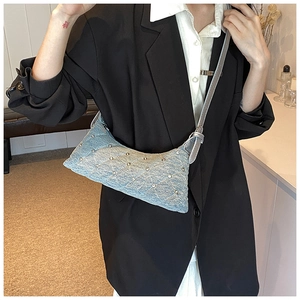 Close-up of light blue denim crescent bag featuring quilted patterns and silver rivets