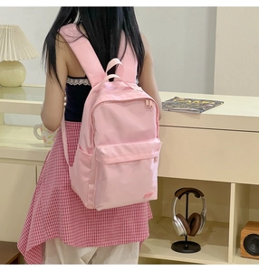 Dettaglio dello zaino in nylon rosa con design multitasche indossato da una modella donna