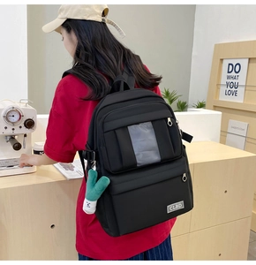 Détail d'un sac à dos en nylon noir avec design multipoches et charm en peluche verte