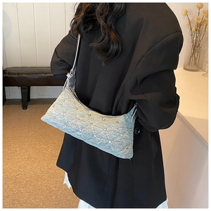 Detail of light blue denim crossbody bag featuring quilted patterns and sparkling rhinestones