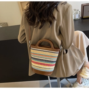 Detail of colorful striped woven bucket bag with brown leather handles and strap