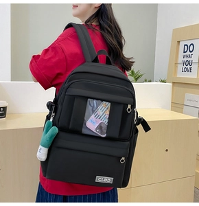 Détail du sac à dos noir en nylon avec poche transparente et breloque peluche verte