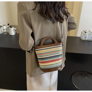 Detail of colorful woven straw bucket bag with brown leather handles and adjustable strap
