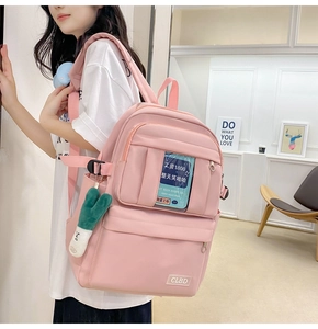 Détail du sac à dos en nylon rose montrant les poches zippées et le pendentif en peluche vert